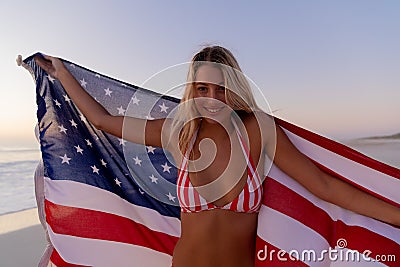 Caucasian woman holding and waving an US flag at the beach. Stock Photo