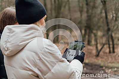 Caucasian woman flying aerial drone in autumn forest. Tech savvy middle age woman. Hobby modern Stock Photo