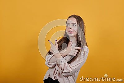 Caucasian woman in pastel shirt keeping hands crossed, pointing fingers aside Stock Photo