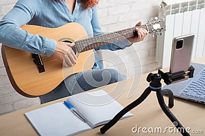 Caucasian woman playing guitar live on a smartphone. The girl leads a music video blog Stock Photo