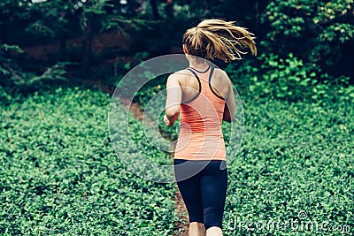 Caucasian woman running on forest trail wearing sport clothes Stock Photo