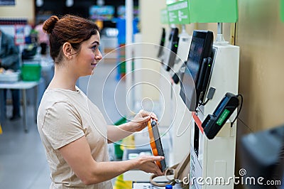 Caucasian woman uses a self-checkout counter. Self-purchase of groceries in the supermarket without a seller Stock Photo