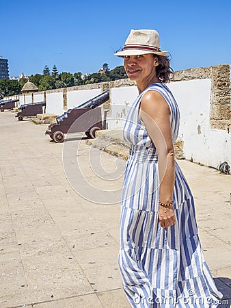 A Caucasian woman walking along an antique Latinamerican marina promenade Stock Photo