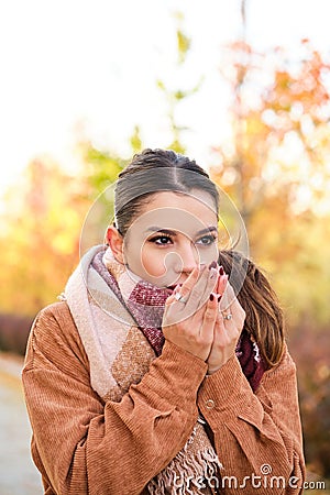 Caucasian woman warming up her hands with her breath during autumn. Stock Photo