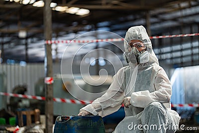 Caucasian woman workers wearing PPE protective clothing and gas masks, goggles, holding old petrol tanks Stock Photo