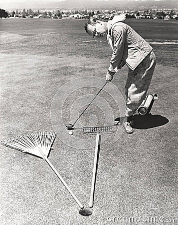 Caught between a rake and a gardening fork on the putting green Stock Photo