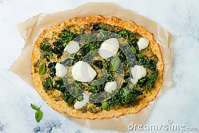 Cauliflower pizza crust with pesto, kale, mozzarella cheese and greens. Stock Photo