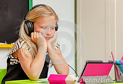 Causacian cute school girl with earphones is on boring online home education. Distance learning concept. Copy space Stock Photo