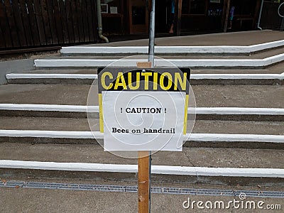 caution bees on handrail sign on steps Stock Photo