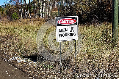 A caution men working sign beside a road Stock Photo