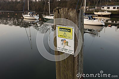 Caution trip hazard, watch your step, sign on the quayside in Caernarfon, Wales. Stock Photo