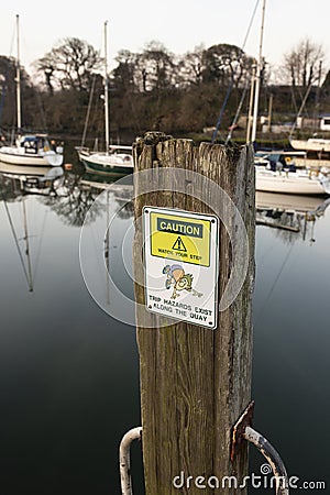 Caution trip hazard, watch your step, sign on the quayside in Caernarfon, Wales. Stock Photo