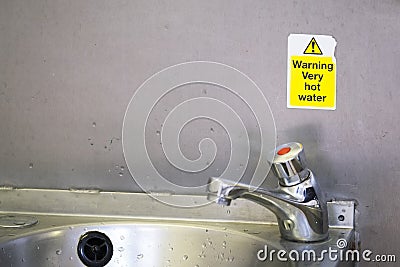 Caution very hot water sign above taps no thermostatic temperature control in public toilets not drinking water Stock Photo