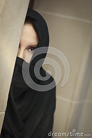 Cautious Islamic Woman in Window Pane Wearing Burqa or Niqab Stock Photo