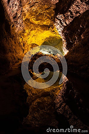 Cave lava tube illuminated with water reflection in Canary Islands Stock Photo