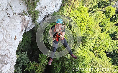 A young woman rappels from a cliff on a guided tour at Caves Branch Lodge in Belize. Editorial Stock Photo