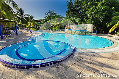 view of hotel grounds with nice inviting swimming pool and people in background in tropical garden Editorial Stock Photo