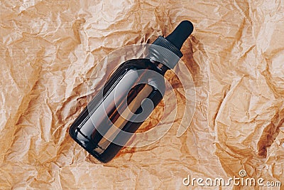 CBD oil bottle, hyaluronic acid tincture on creased cardboard. Serum with collagen and peptides on wrinkled crumpled Stock Photo