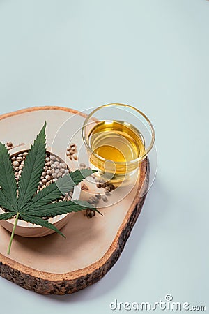 Legalized CBD oil THC tincture in glass bowl with seeds and a hemp leaf on top. Stock Photo