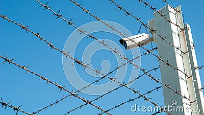 CCTV surveillance security camera video equipment on barbed wire fence of security control area and copy space Stock Photo