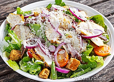 Ceasar salad with grilled chicken fillets, red onion rings, lettuce, orange cherry tomatoes, croutons, grated parmesan Stock Photo