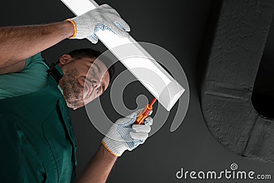 Ceiling light. Electrician installing led linear lamp indoors, bottom view Stock Photo