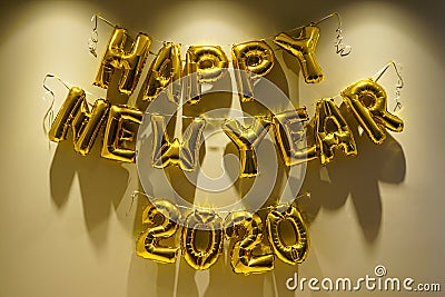 Celebrating the New Year 2020. Gold foil balloons on a yellow background. Foil balls Stock Photo