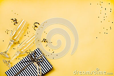 Celebration background - top view of two chrystal champagne glasses, a gift box wrapped in black and white striped paper, ribbons Stock Photo