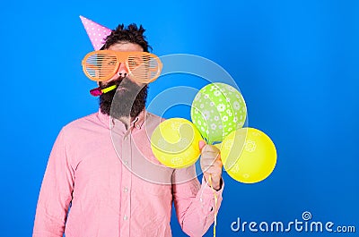 Celebration concept. Hipster in giant sunglasses celebrating birthday. Man with beard and mustache on calm face blows Stock Photo
