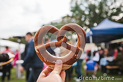 Celebration of the famous German beer festival Oktoberfest. The person holds in his hand a traditional pretzel called Stock Photo