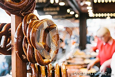 Traditional pretzels called Brezel hang on the stand against the background of a blurred street market and people on Stock Photo