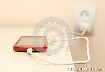 Cell phone is being charged from the electrical outlet Stock Photo