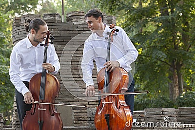 Cellist musician group perform music in the street, close up man playing violin Stock Photo