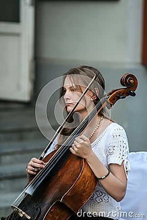 Cellist woman playing on the street, side view. Editorial Stock Photo