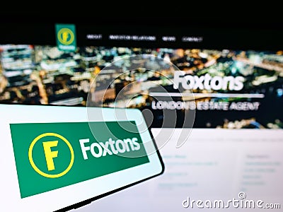 Cellphone with logo of British real estate agency Foxtons Group plc on screen in front of business website. Editorial Stock Photo