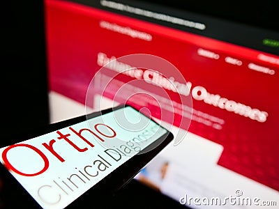 Cellphone with logo of US medical diagnostics company Ortho Clinical Diagnostics on screen in front of website. Editorial Stock Photo