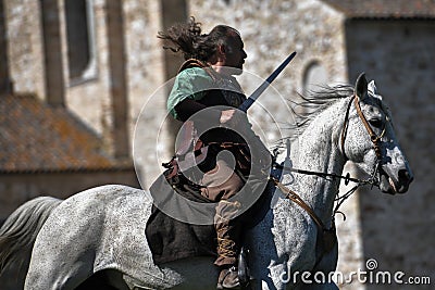 A Celtic Knight in traditional costume holds a sword and rides a horse Editorial Stock Photo