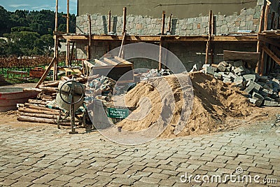 Cement mixer with wooden scaffolding and sand pile Editorial Stock Photo