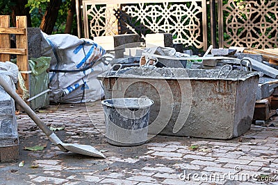 Cement, shovel and cement tub in construction site. Constuction details. Construction site: tools, sand, bricks, tile, pedestrian Stock Photo