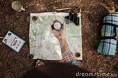 A girl is holding a compass to orientate in the forest with a map. Stock Photo