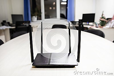 In the center of the frame is the router in black on a light wooden table, access to the Internet in this room Stock Photo