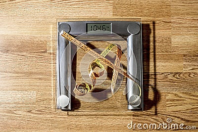 The centimeter tape is on the scale showing a lot of kilograms Stock Photo