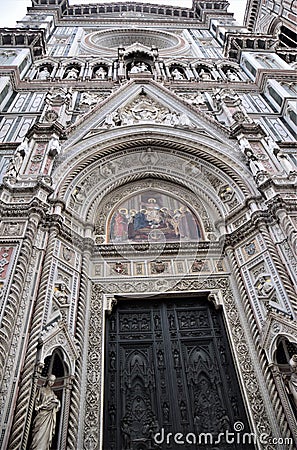 Central part of the facade of the Cathedral of Santa Maria del Fiore, with the large dark door, the large fresco and the rose wind Stock Photo