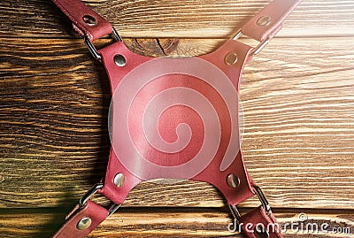 Central part pink camera harness, multi-camera strap harness, leather camera strap on brown wooden background. Glare. Stock Photo