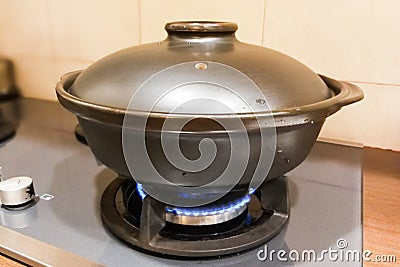 Ceramic clay pot on gas fire generated stove Stock Photo