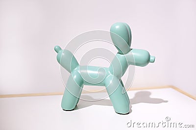 Ceramic dog doll on a white background. statuette of a dog in mint color stands on a table against a white wall in the interior of Stock Photo