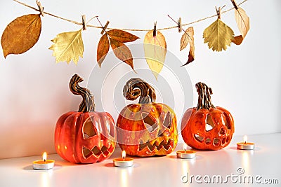 Ceramic Jack Lanterns and autumn leaves garland. Halloween composition. Home decor Stock Photo