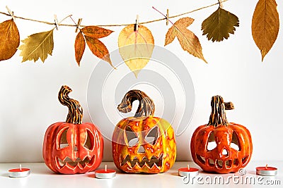 Ceramic Jack Lanterns and autumn leaves garland on table wall background. Home decoration Stock Photo