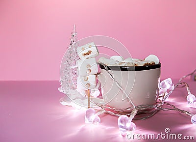 Ceramic mug with hot fresh cocoa drink and handmade funny marshmallow snowman on soft pink background Stock Photo