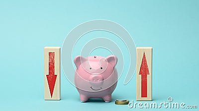 Ceramic pink piggy bank and wooden blocks with red down and fan arrows. The concept of fluctuating bank interest, falling and Stock Photo